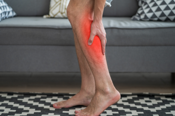 A man reaches down to grab his leg, animated in red to symbolize pain from PAD symptoms.